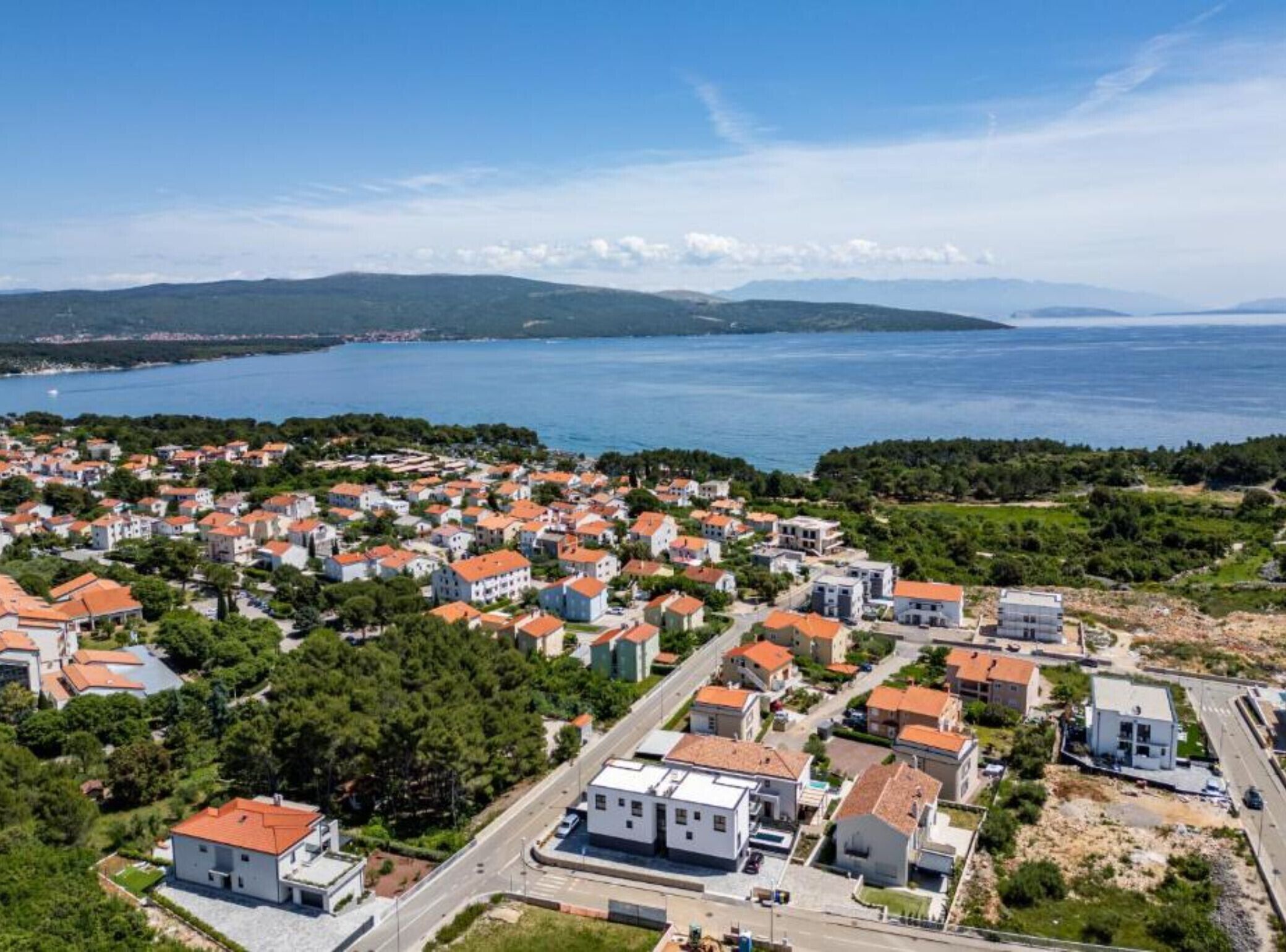 Une vue aérienne d’une ville côtière, avec de nombreux bâtiments, des routes et une vaste étendue d’eau.