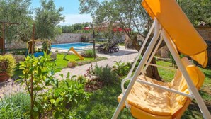 A backyard with a swimming pool, a swing set, and a yellow chair. - Holiday Home Luna - Holiday Home (Vodnjan)