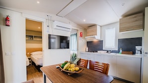 Una cocina compacta con comedor, microondas, estufa y refrigerador pequeño.