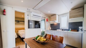 Una cocina compacta con comedor, microondas, estufa y refrigerador pequeño.