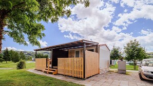 Eine kleine Holzhütte mit Veranda und überdachter Außenbereich, ein Auto in der Nähe geparkt.