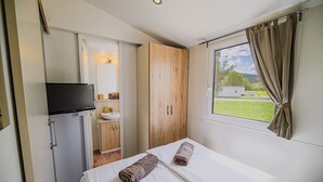 Ein Schlafzimmer mit Bett, Schrank, Fernseher und einem fenster mit Vorhängen.