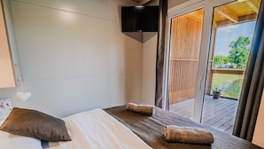 Une chambre à coucher avec un lit, des oreillers, une télévision et une vue sur l’extérieur.