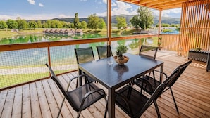 Un espace extérieur abrité, doté d’une table et de chaises, qui offre une vue sur un lac et un terrain de golf.