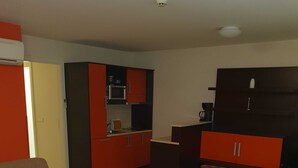 Una habitación de hotel con cama, sofá, kitchenette pequeño y escritorio.