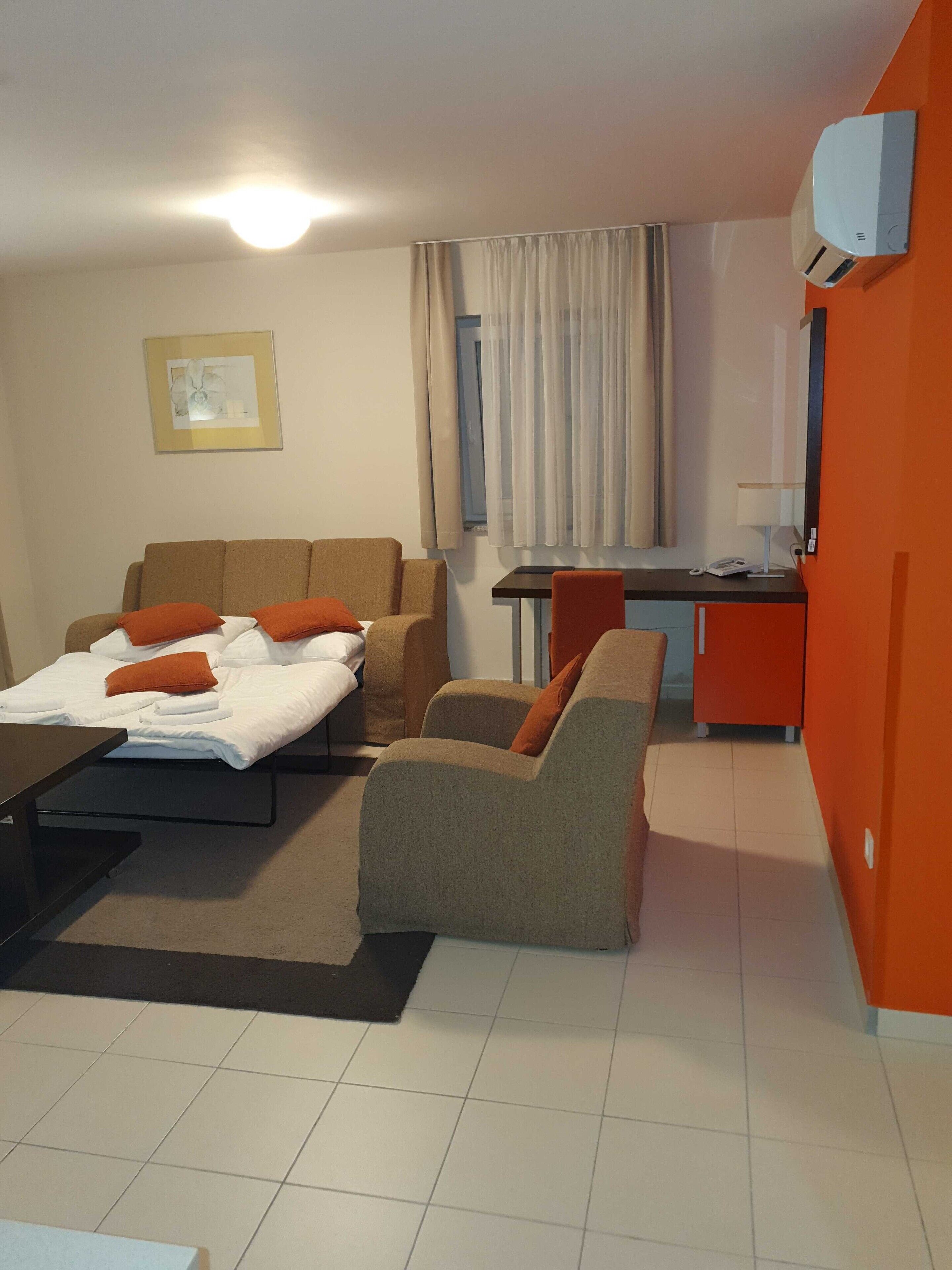 Une chambre d’hôtel avec un lit, deux canapés, un bureau et une petite table.