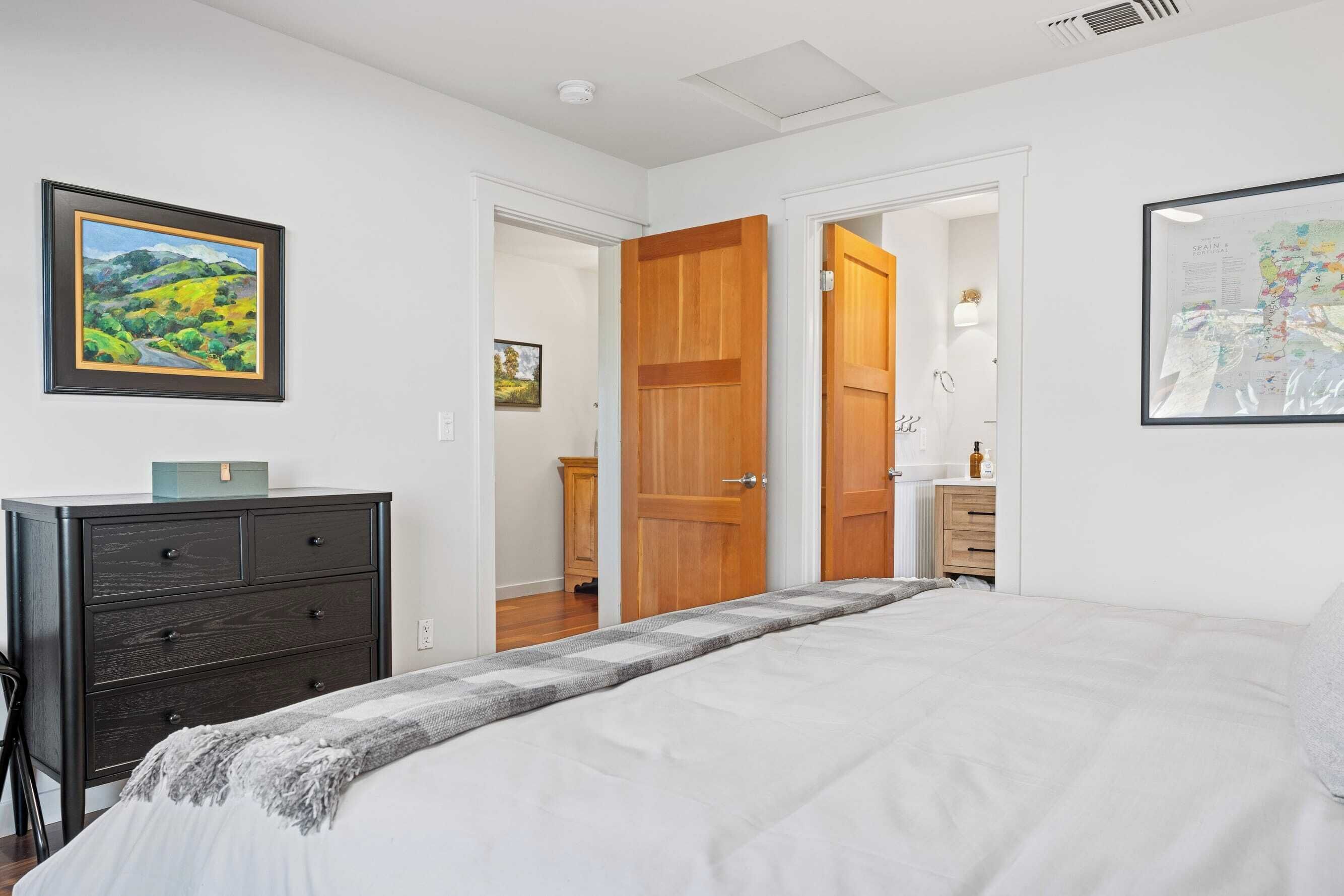 A bedroom with a bed, a dresser, and a door leading to another room.