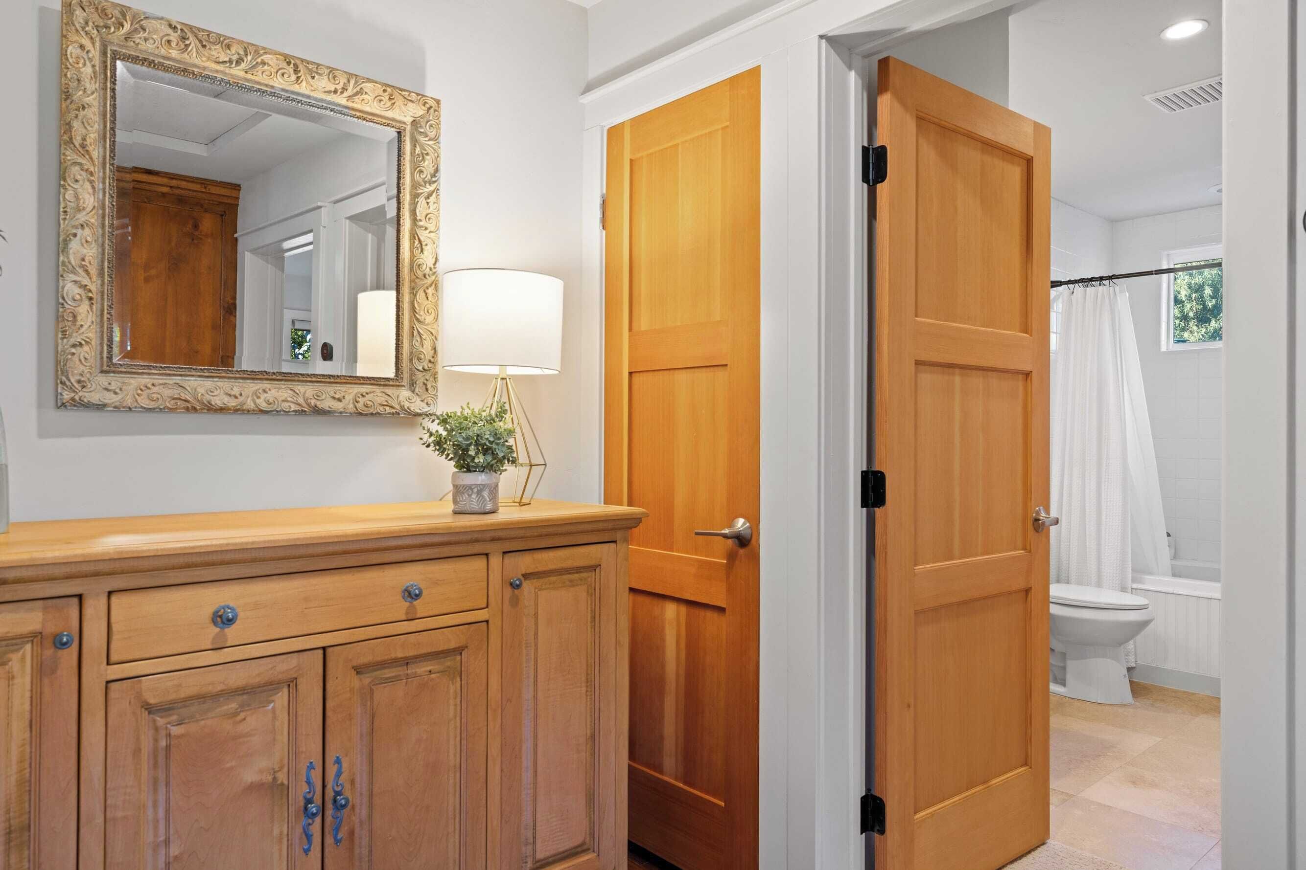 A bathroom with a wooden door, a white toilet, and a shower curtain.
