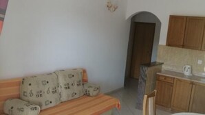 A room with a sofa, a small table, and a kitchenette.