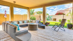 An outdoor patio with a sectional sofa, a round coffee table, and a single chair.