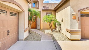 A residential area with two garage doors, a pathway, and two palm trees.