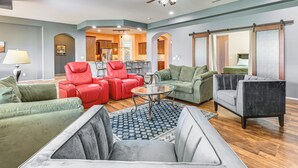 A spacious living room with a ceiling fan, a dining area, and a kitchen in the background.