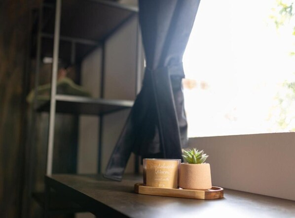 Une étagère en bois avec une bougie, une petite plante en pot et un chandelier.