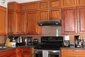 Una cocina con armarios de madera, una estufa de acero inoxidable, una cafetera y un tostador.