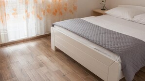 A bedroom with a bed, a nightstand, a lamp, and a window with sheer curtains. - One-Bedroom Apartment With Sea View Ap 2 (Sevid)