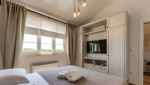 A bedroom with a bed, a TV mounted on a wooden cabinet, and a window with curtains. - Rustic Villa Perosa With Heated Pool (Zaton)