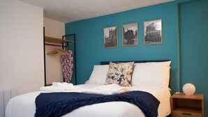Un dormitorio con cama, mesita de noche, armario y una pared con tres cuadros enmarcados.