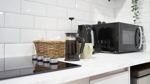 Una encimera de cocina con una cafetera, un microondas, una cesta y una taza.