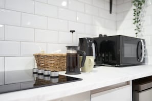 Un comptoir de cuisine avec une machine à café, un four à micro-ondes, un panier et une tasse.