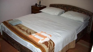 A neatly made bed with a floral-patterned bedspread and a folded towel on the side. - Two-Bedroom Apartment With Sea View (Malinska)