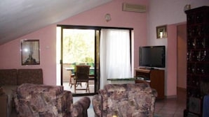 A living room with a sofa, a television, and a bookshelf. - Two-Bedroom Apartment With Sea View (Malinska)