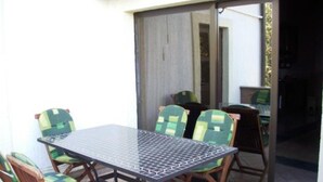 A dining area with a metal table and wooden chairs with green cushions. - Two-Bedroom Apartment With Sea View (Malinska)