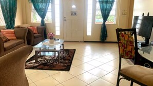 A living room with a sofa, coffee table, and a television. - Anne Marie Villas - Ron (Castries)