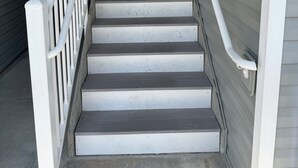 A staircase with white railings and a metal handrail, leading to an exit door at the top.