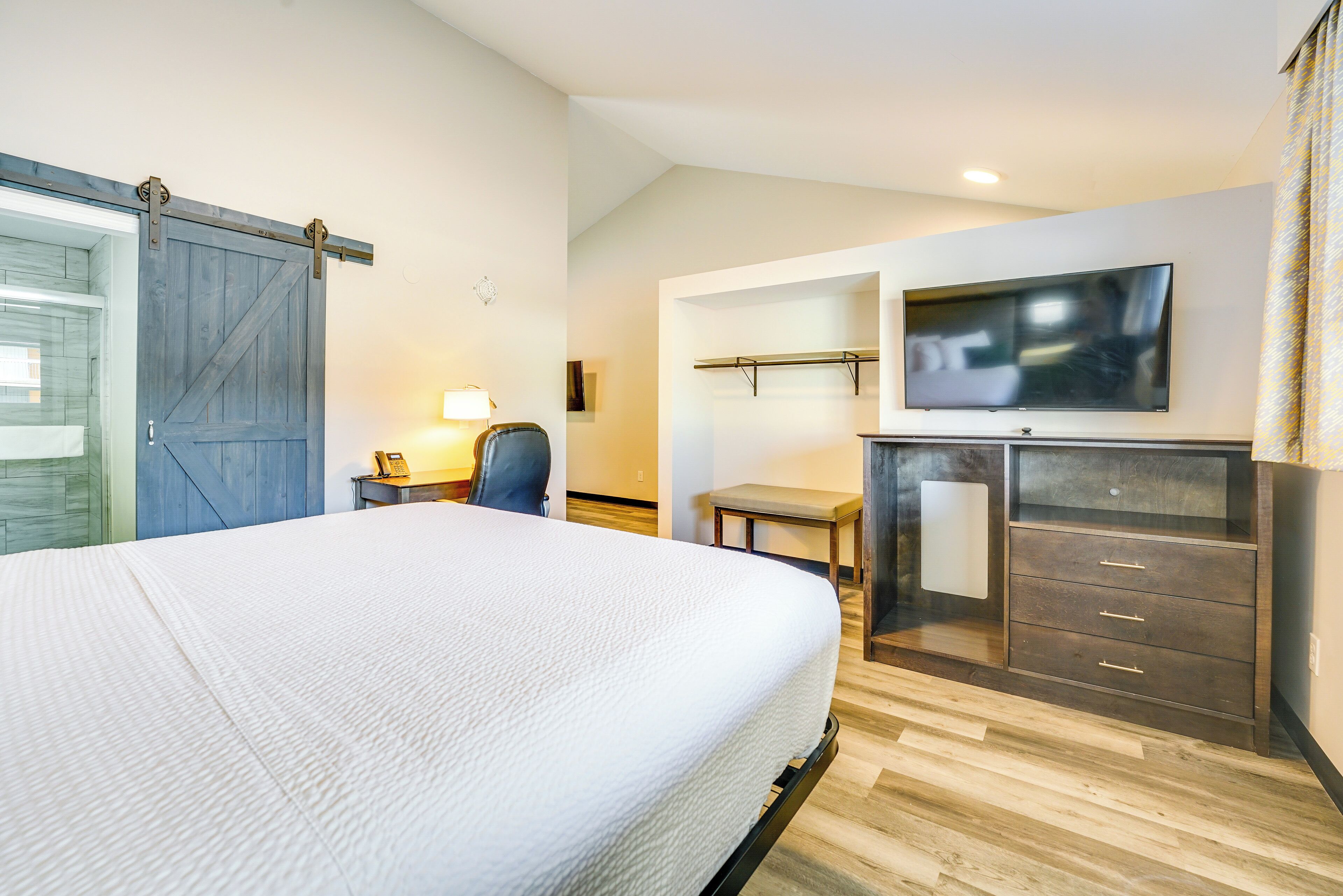 A hotel room with a bed, a desk, a chair, a TV, and a wardrobe.