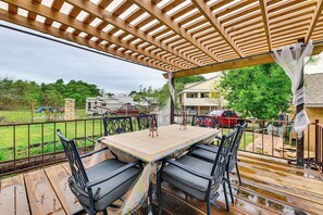 A covered patio with a table and chairs, a wooden deck, and a view of a residential area with houses and a fence. - Spacious Family Home w/ Fenced Yard in DFW Area (Flower Mound)