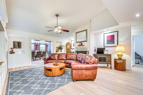 A spacious living room with a leather sectional sofa, a round coffee table, and a fireplace. - Spacious Family Home w/ Fenced Yard in DFW Area (Flower Mound)