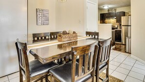 A dining area with a wooden table and chairs, a hanging light fixture, and a kitchen in the background. - 5 Mi to Eagle Creek Park: Home w/ Fenced Yard! (Indianapolis)