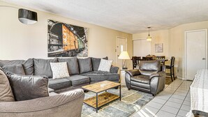 A living room with a gray sofa, a wooden coffee table, a leather armchair, and a dining area with a table and chairs. - 5 Mi to Eagle Creek Park: Home w/ Fenced Yard! (Indianapolis)
