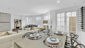 A dining area with a wooden table set for four, surrounded by modern chairs. - Central Snug With Patio By My Getaways (Worthing)