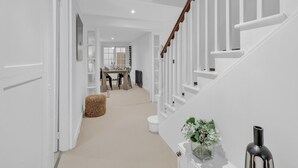 A hallway with a staircase leading to a dining area. - Central Snug With Patio By My Getaways (Worthing)