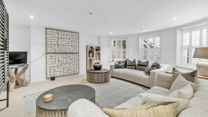 A modern living room with a sofa, coffee table, and decorative items. - Central Snug With Patio By My Getaways (Worthing)