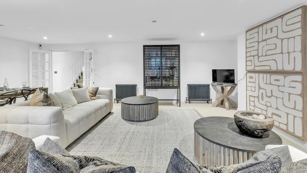 A modern living room with a sofa, a round coffee table, and a TV. - Central Snug With Patio By My Getaways (Worthing)