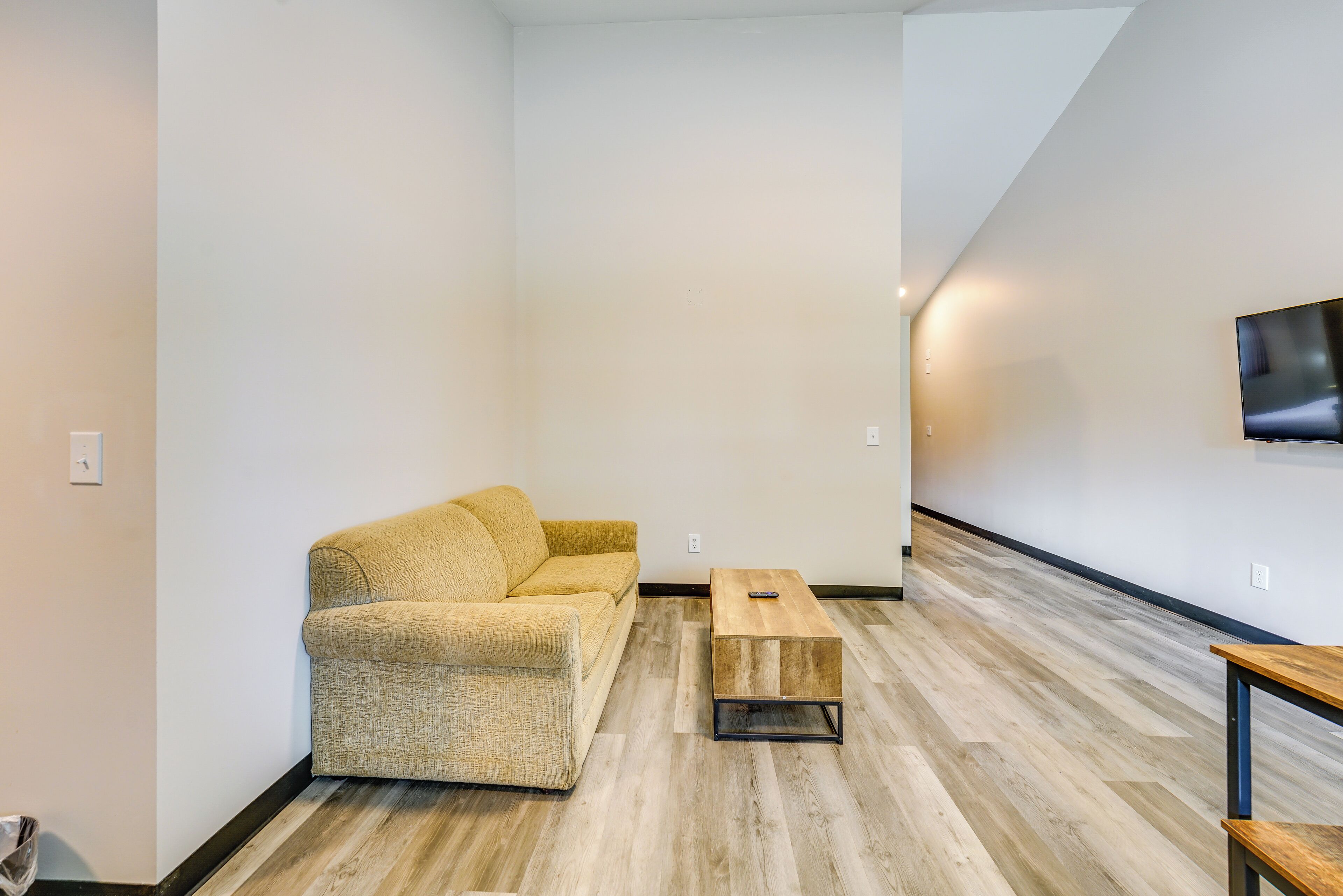 A modern living room with a sofa, a coffee table, and a TV mounted on the wall.