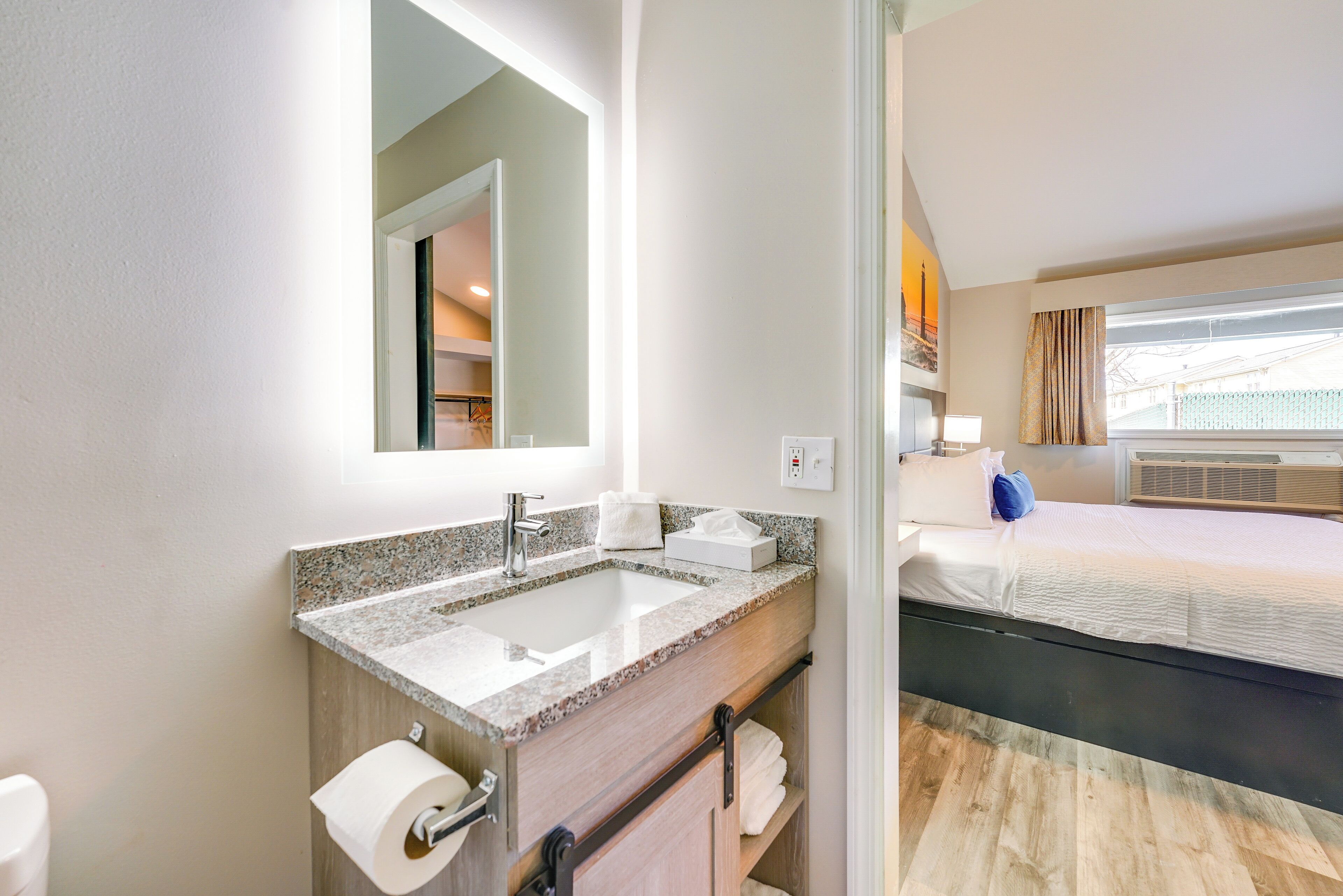 A modern bathroom with a granite countertop sink, a mirror, and a toilet.