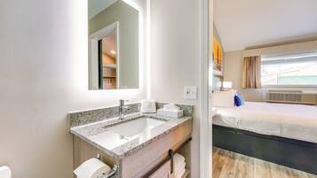 A modern bathroom with a granite countertop sink, a mirror, and a toilet.