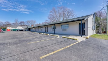 A motel with a parking lot, a row of rooms, and a building with a green roof.