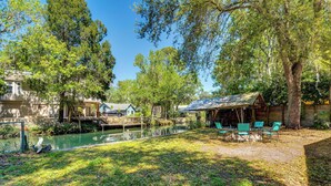 A rustic cabin with a dock extending into a calm river, surrounded by lush greenery and trees. - Boat Slip & Fire Pit: Peaceful Homosassa Home (Homosassa)