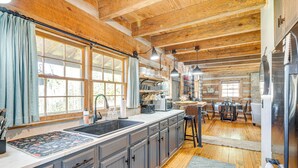 A spacious kitchen with wooden beams, a large window, and a sink. - Hot Tub, Fire Pit & Creek Access: Whittier Cabin! (Whittier)