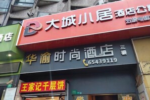 A hotel with a red and black sign, a contact number, and a visible entrance. - Shanghai Hua Yu The Tophams Hotel (Shanghai)