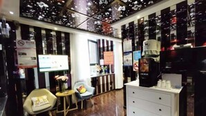 A modern interior with a seating area, a coffee machine, and a counter with various items. - Shanghai Hua Yu The Tophams Hotel (Shanghai)