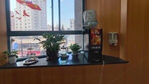 A hotel room with a large window, a wooden desk, and a coffee machine. - Shanghai Hua Yu The Tophams Hotel (Shanghai)