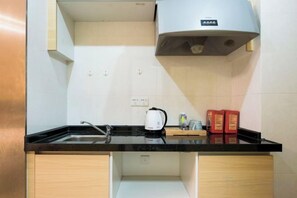 A kitchen with a black countertop, a kettle, and a coffee maker. There are wooden cabinets below the countertop. - Guangzhou Jingting Humanities Inn (Pazhou Convention and Exhibition Center) (Guangzhou)