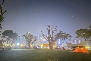 A nighttime outdoor event with tents and trees, set against a city skyline. - Guangzhou Jingting Humanities Inn (Pazhou Convention and Exhibition Center) (Guangzhou)