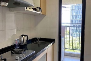A kitchen with a black countertop, a kettle, and a water bottle. - Guangzhou Jingting Humanities Inn (Pazhou Convention and Exhibition Center) (Guangzhou)
