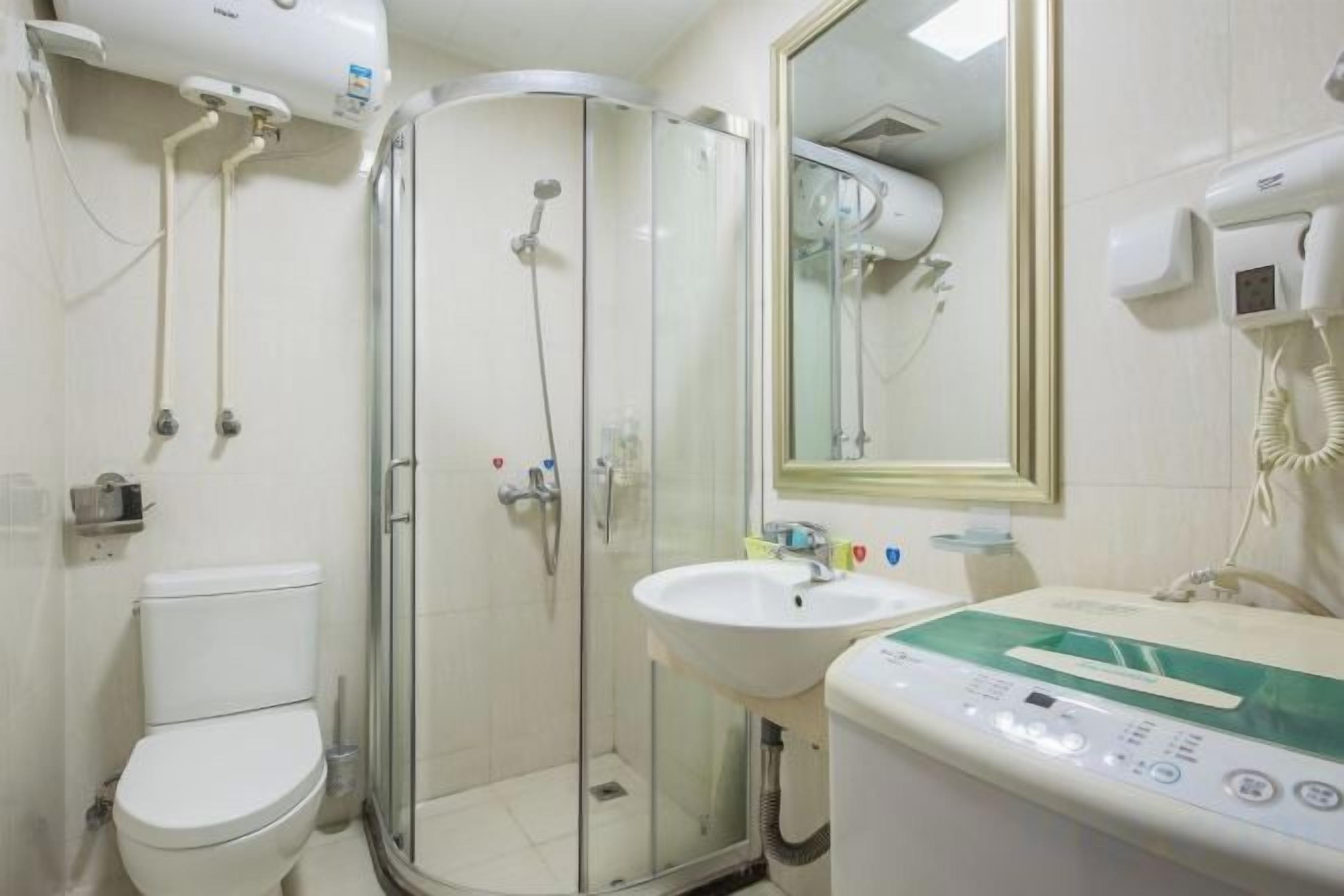 A bathroom with a toilet, a glass-enclosed shower, a sink, and a mirror.